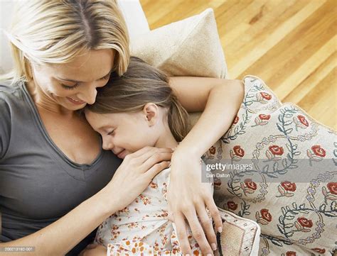 Mother On Sofa Embracing Sleeping Daughter Elevated View High Res Stock