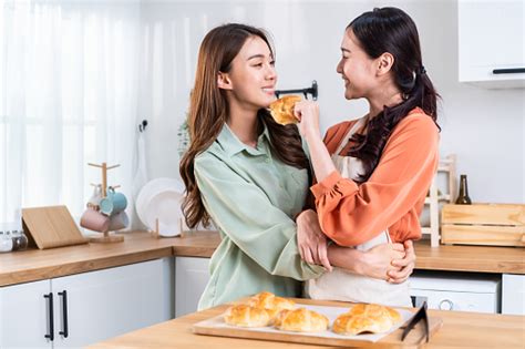 asian beautiful lesbian woman couple look at girlfriend bake croissant attractive two female gay