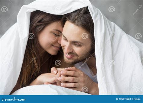 Tender Couple Relaxing Under Blanket On Sunday Morning In Bed Stock