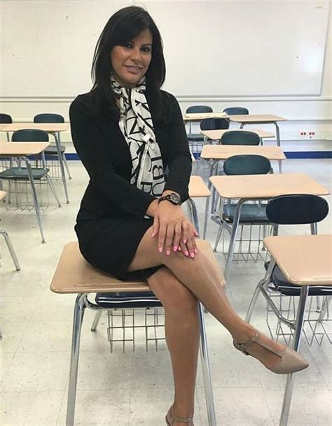 A Woman Sitting On Top Of A Desk In A Classroom