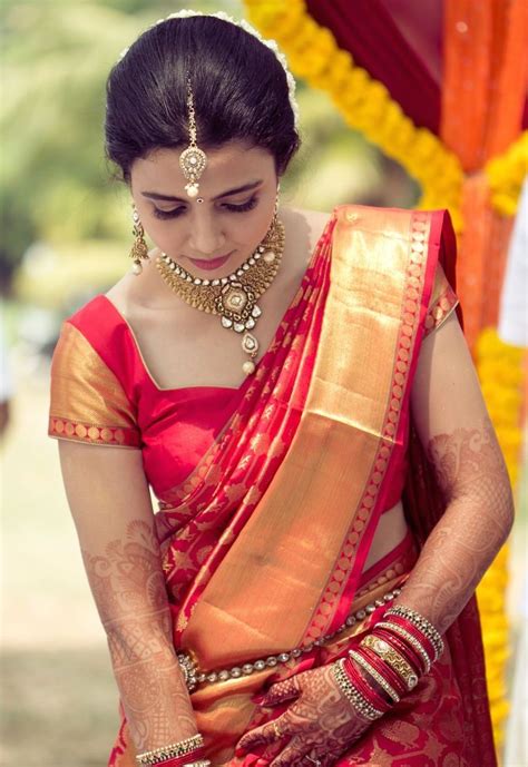 A Woman In A Red And Gold Sari Is Looking Down At Her Hand While She Wears