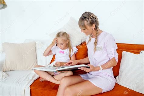 La Madre Se Sienta En Un Sofá Y Lee Un Libro Con Su Hija En Una