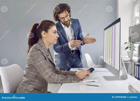 Manager Talking To Office Trainee Who Is Working With Spreadsheets On