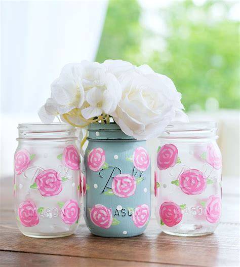 Three Painted Mason Jars With Flowers In Them