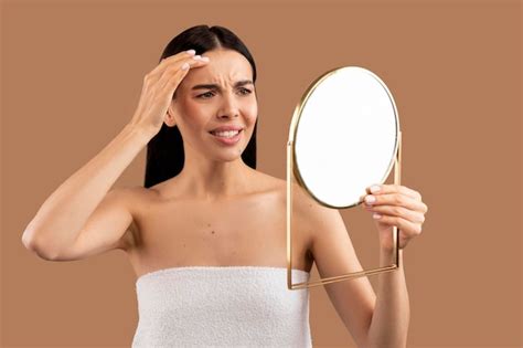 Mujer semidesnuda molesta mirando al espejo y tocándose la cara Foto Premium