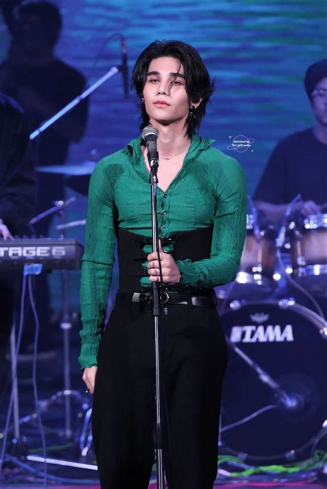 A Woman In Green Shirt And Black Pants Standing Next To A Microphone