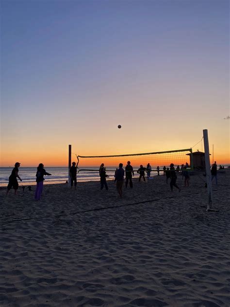 People Playing Volleyball On The Beach At Sunset