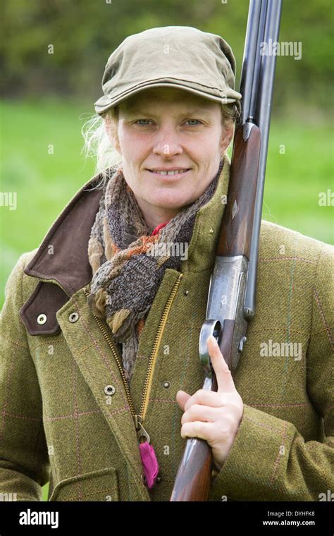 A Woman Wearing Shooting Clothing And Standing Outside In The English Countryside With A Shotgun
