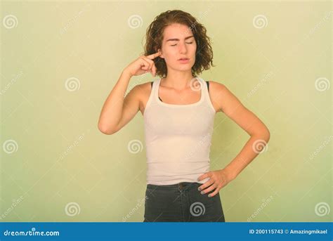 Studio Shot Of Beautiful Teenage Girl Covering Ear With Finger And Eyes
