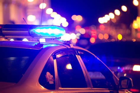 Blue Light Flasher Atop Of A Police Car City Lights On The Background