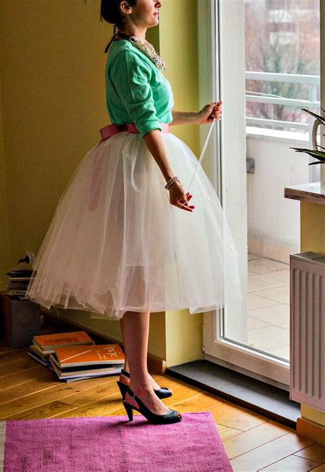 A Woman Standing In Front Of A Window Wearing A White Tulle Skirt And