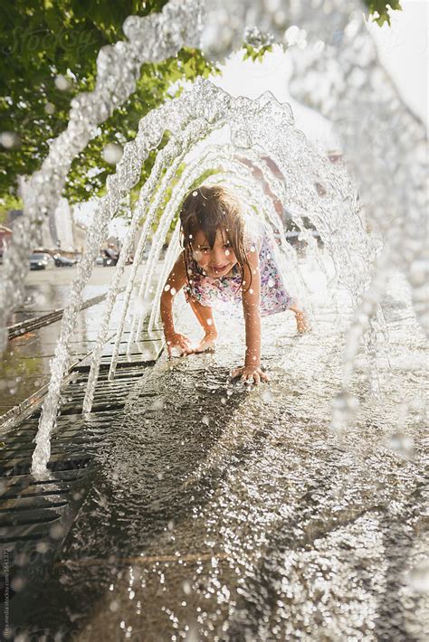 Girl Getting Wet While Passing Underneath Fountain In City Square By