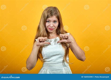 Attractive Blonde Young Woman Spreads Fists At Herself Looking Aside