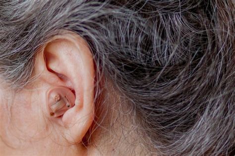 Premium Photo Senior Woman Inserting Hearing Aid In Her Ears