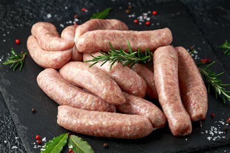 Freshly Made Raw Butchers Sausages In Skins With Herbs On Stone Board