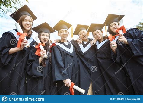 Happy Students In Graduation Gowns Holding Diplomas On University