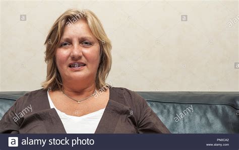 Portrait Of Mature 59 Year Old Woman With Happy Expression At Home On Sofa Looking At Camera