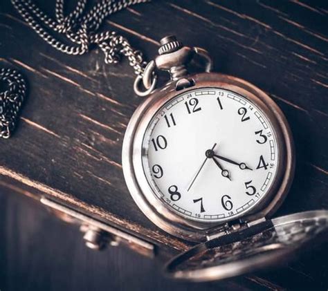 An Old Pocket Watch Sitting On Top Of A Wooden Table