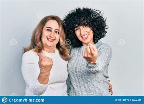 Middle East Mother And Daughter Wearing Casual Clothes Beckoning Come Here Gesture With Hand