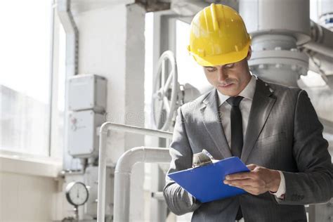 Young Male Supervisor Writing On Clipboard In Industry Stock Image