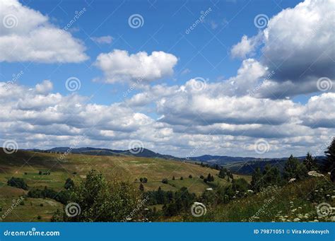 White Fluffy Clouds In The Blue Sky Over The Green Mountains Stock