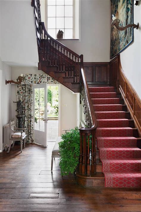A Staircase With Red Carpet And Wooden Handrails Leading Up To The