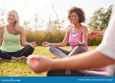 Group Of Mature Men And Women In Class At Outdoor Yoga Retreat Sitting