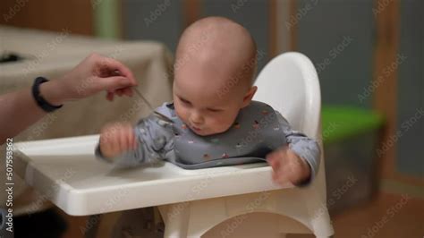 Mother Feeding Baby Boy In High Chair Mother Feeds Her Little Son From