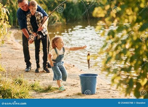 Chica Metiendo Pescado En El Cubo Padre Con Hijo E Hija Pescando