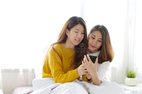 Young Cute Asia Lesbian Couple Using Smart Phone With Happiness At Home