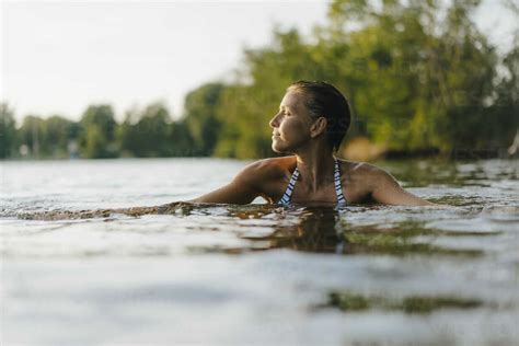 Woman Swimming In A Lake At Sunset Stock Photo