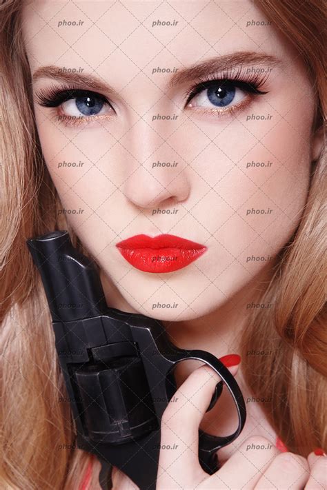 عکس با کیفیت زن با چهره زیبا و رژ قرمز و چشم های آبی و اسلحه در دست