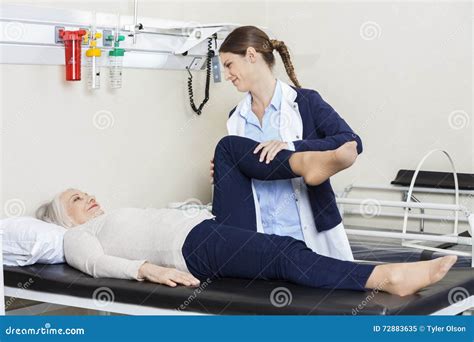 Young Physiotherapist Helping Senior Woman With Leg Exercise Stock Image Image Of Assistance
