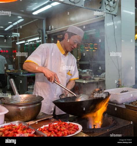 cook prepares food over flaming wok at sidewalk food stand in muslim quarter of xi an china
