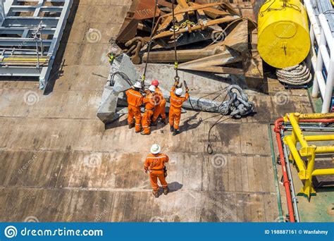 A Team Of Rigger Lifting An Anchor From A Construction Work Barge