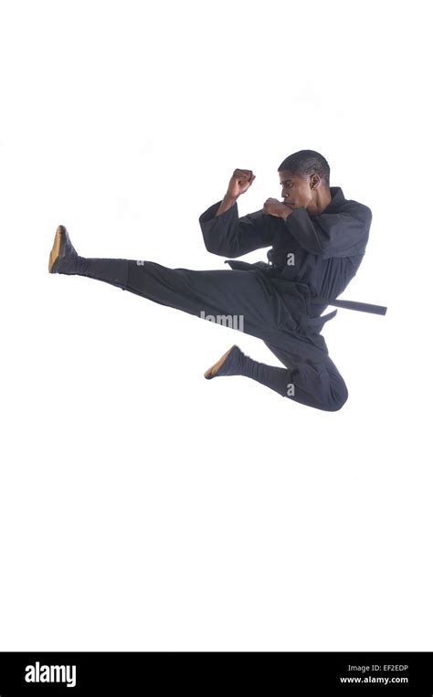 Young Man Wearing A Karategi Doing A Karate Kick In The Air Stock Photo