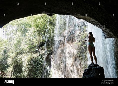 Woman In Bikini Sit On Rock Under Falling Water Of Suwat Waterfall In
