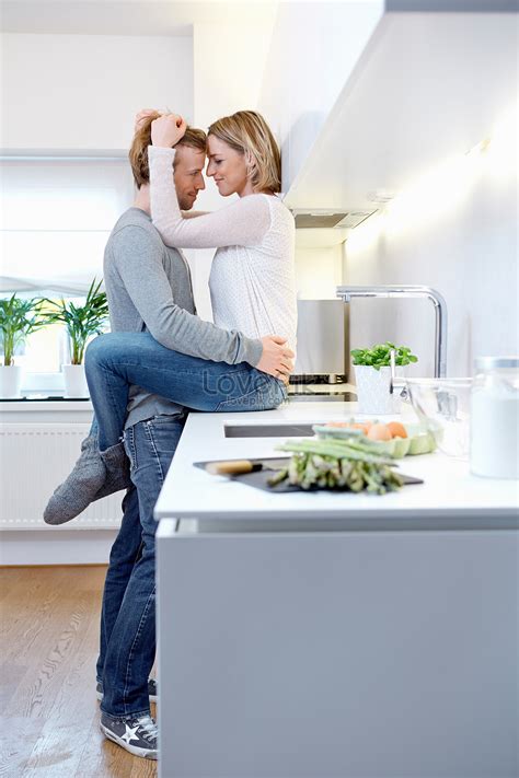 couple in kitchen hugging woman sitting on kitchen counter picture and hd photos free download
