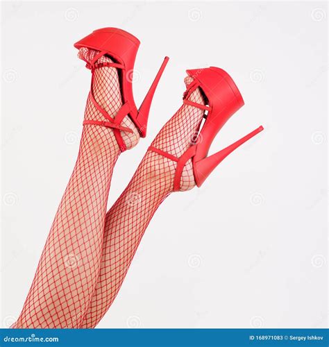 Female Legs In High Heel Red Striptease Shoes And Fishnet Stockings