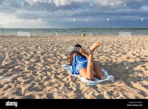 Rear View Of Pretty Girl Lying On Sandy Beach On Hot Summer Stock Photo