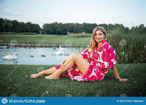 Beautiful Smiling Blonde Woman Lying On The Grass Outdoors She Is