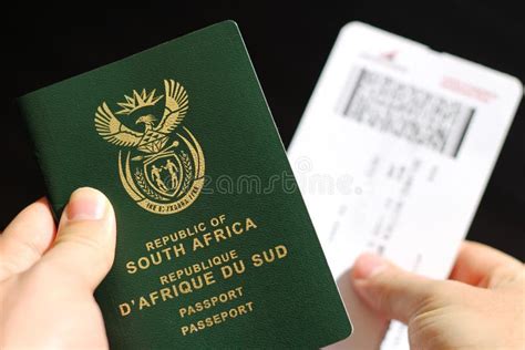 High Angle Shot Of A Person Holding A Passport And A Plane Ticket Over A Black Background Stock