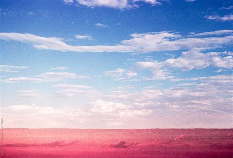 Surreal Red Landscape Under A Blue Sky Filled With Clouds Del