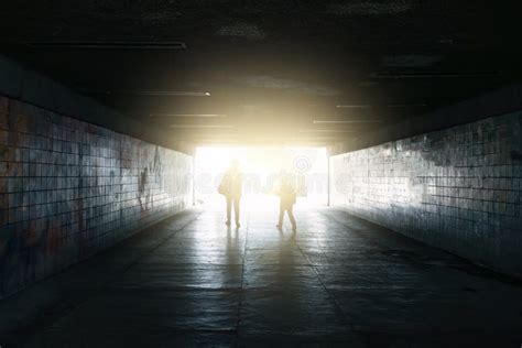 Silhouettes Of Woman And Kid Walk To Light In End Of Underground Tunnel