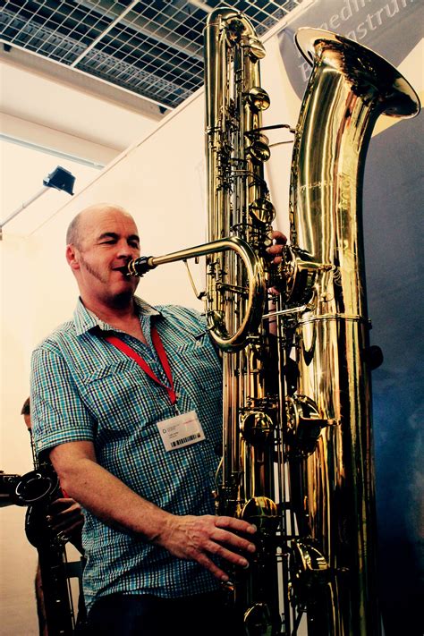 A Man Standing Next To A Large Brass Instrument