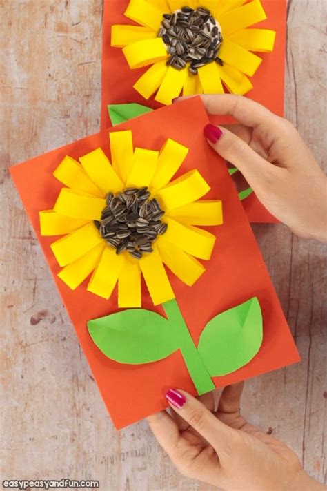 Two Sunflowers Made Out Of Construction Paper Are Being Held By Someone