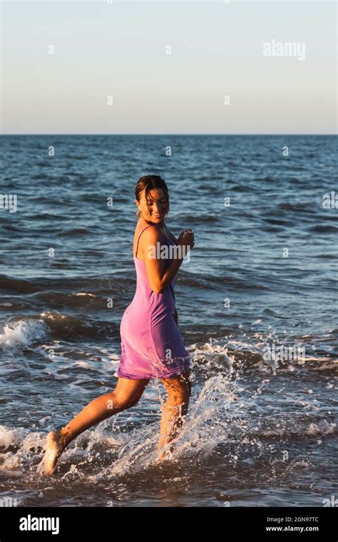Playful Woman Splashing Water While Running On Beach Stock Photo Alamy