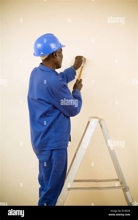 african american construction worker handyman carpenter standing on ladder working with