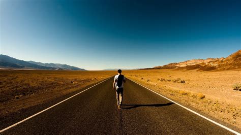 Man Walking On Middle Of Road Surrounded By Desert Road Desert