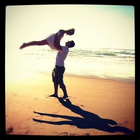 Two People Are Playing On The Beach With One Person Upside Down In The Air